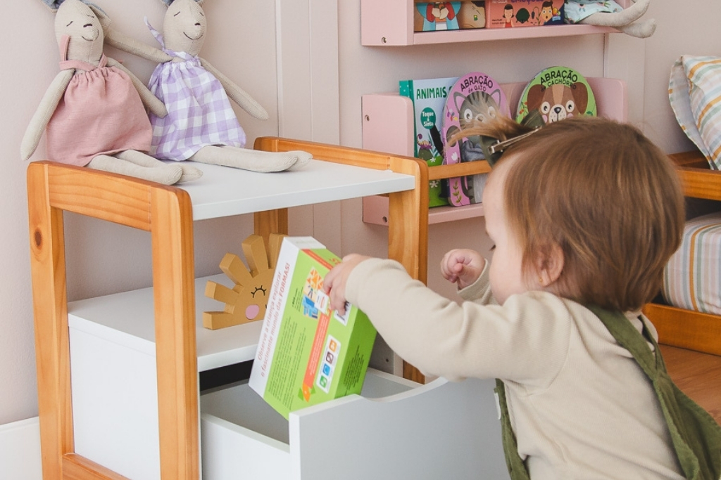 Criança de 2 anos brincando com brinquedos organizados em prateleira baixa