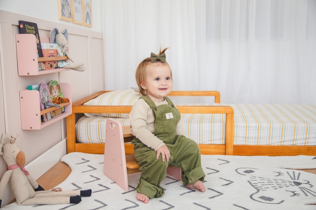 Quarto de bebê organizado com tapete e prateleira baixa com brinquedos